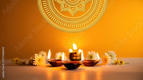 Happy Diwali Group of traditional lit clay diyas with white flowers and golden mandala pattern on warm orange background for Diwali greeting