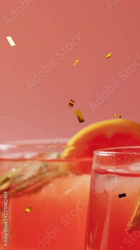 Animation of confetti falling and cocktail on pink background