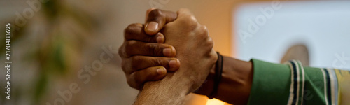 Canvas Print Diverse young adult male football fans clasping hands in strong grip, celebrating victory and showing unity