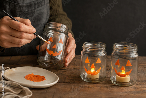 Hand painting jack o lantern faces on upcycled glass jars