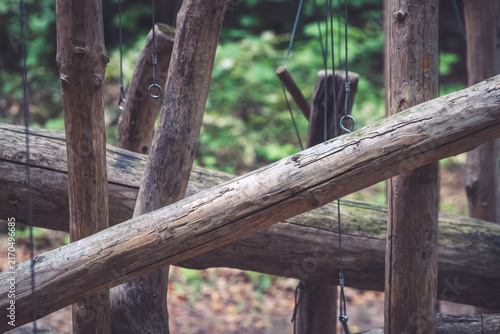 Wooden structure in forest with ropes and natural light shining through trees