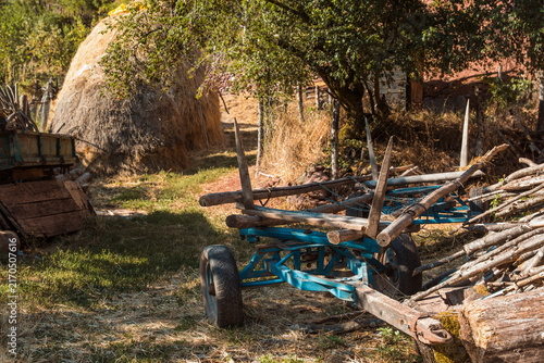 Photography Traditional wooden farm cart painted blue next to a haystack and firewood pile in a rustic yard at Topli Do village in Stara Planina nature reserve, Serbia