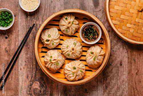 Fotografie Steam basket with dumplings served with dipping sauce on a wooden table
