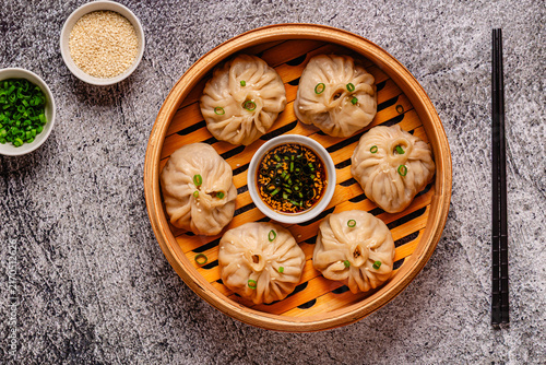 Steamed dumplings served in a bamboo basket with dipping sauce
