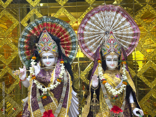 Fotografie Gilded altar with three ornate statues of Hindu deities adorned with garlands and umbrellas