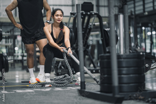 Asia woman exercising with battle ropes or training sled pull in gym