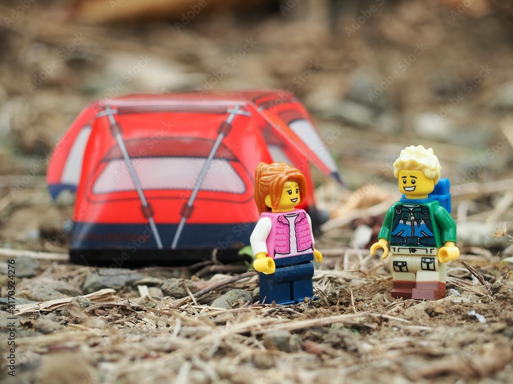 Fototapeta premium Indonesia - May 9, 2023 : Mini toy of action figure at grassland with blurred background. Toy photography concept. Camping with tent at outdoor conceptual design. Man and Woman character.