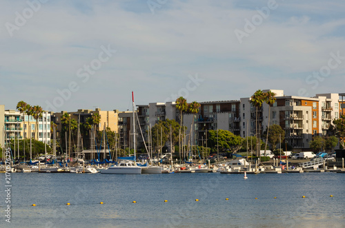 Modern waterfront marina with sailboats luxury apartments palm trees and coastal urban lifestyle on sunny California bay