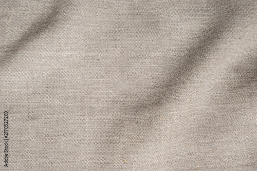 Natural beige linen fabric texture background with soft waves, beautiful cloth pattern surface for design overlay and backdrop material.