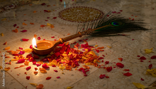 Traditional oil lamp diya with peacock feather on flower petals tradition festival celebration religious spirituality spiritual meditation ceremony blessing devotion traditions hinduism
