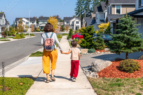 Mother and son walking hand in hand through suburban neighborhood