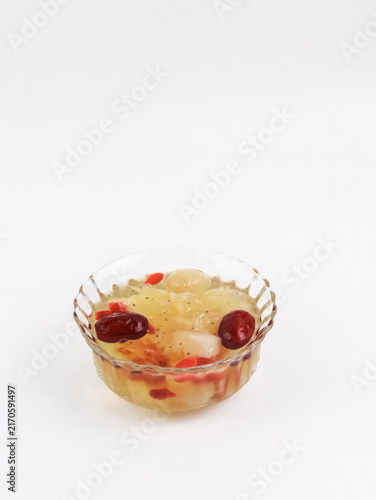 A vertical studio shot of a traditional Asian sweet dessert soup filled with snow fungus, red dates, goji berries, and chia seeds, served in a clear glass bowl against a clean white background.