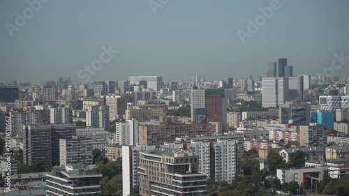 Panoramic elevated daytime cityscape with dense midrise and highrise buildings under hazy blue sky, with cityscape, skyline, urban, building detail, showing architecture, residential,commercial