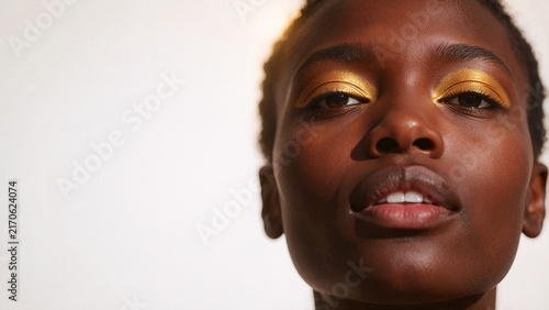 Stunning Portrait of Young Black Woman with Golden Eyeshadow Makeup on White Background