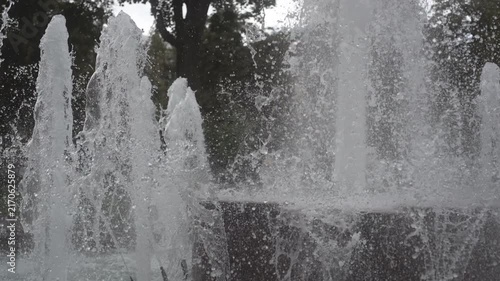 Close frontal view of fountain jets fragmenting into dense spray and droplets in urban park, with fountain, water, jets, spray detail, showing droplet, plume,splash, mist context