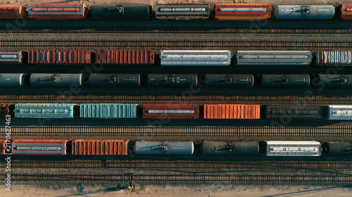 Aerial top-down view of a busy freight rail yard with colorful cargo train cars on tracks.