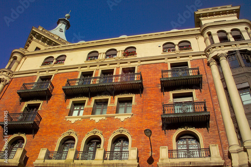 Ornate brick building architecture with balconies and spire in city. Spain - Burgos