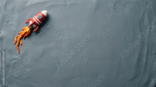 Clay rocket ship launching on a gray background.