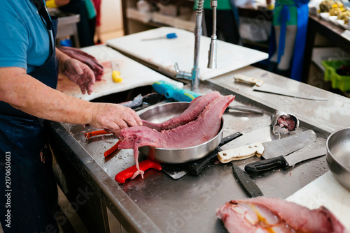 Man cleaning fresh fish at market counter