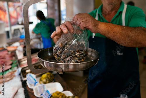 Fishmonger weighing fresh mussels at a seafood market