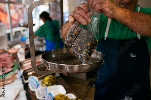 Fishmonger weighing fresh barnacles at a local market.