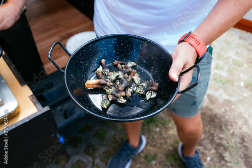 Person holding pan with goose barnacles for outdoor cooking