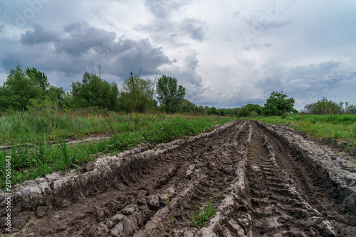 Konstfotografi A dirt road surrounded by meadows and trees, strewn with puddles and potholes after the rain