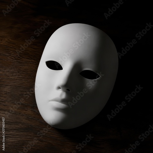 Plain white theatre mask lying face up on a dark table