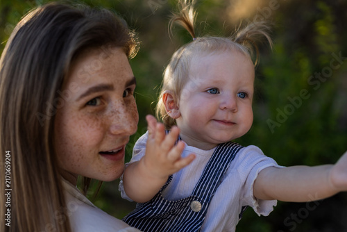 Fotografía Mother holding her baby daughter outdoors in warm sunlight