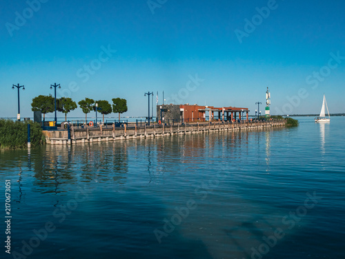Foto Waterfront pier with sailboat under a clear blue sky