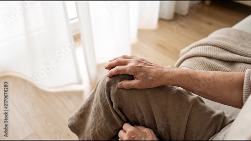 Knee pain from osteoarthritis affects older adult at home, with hands gently supporting joint, worried expression, leg discomfort, arthritis symptoms, and limited mobility during daily activities