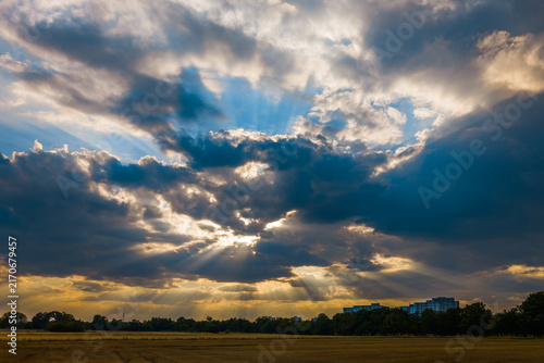 Bright rays of sunshine from the sun hidden behind dark clouds