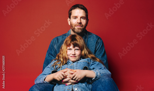Sitting together, father and daughter show a close family bond in the studio