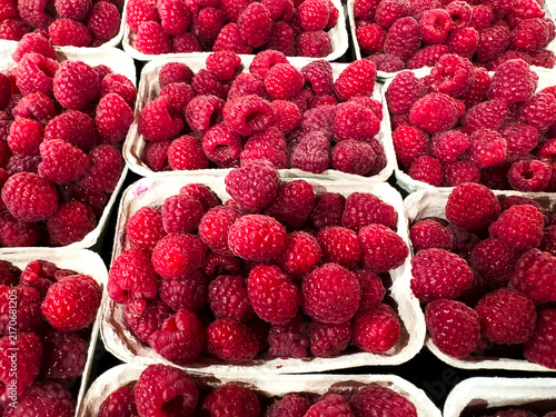Foto Fresh ripe raspberries in cardboard punnets at a market, harvest concept