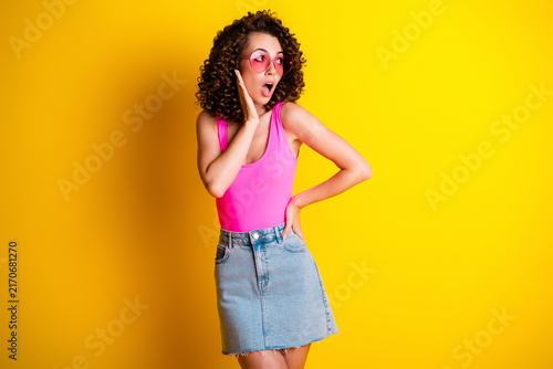 Canvastavla Surprised young woman in pink top and denim skirt posing with heart sunglasses a