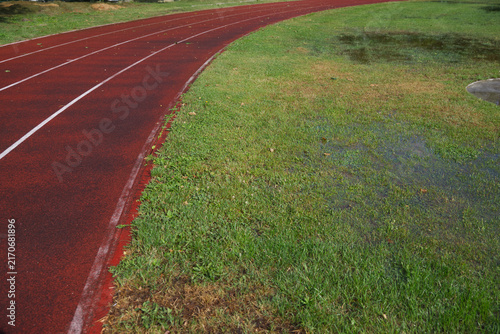 Athletics track after heavy rain with flooded grass, making outdoor training difficult in autumn