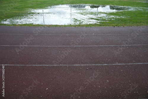 Athletics track after heavy rain with flooded grass, making outdoor training difficult in autumn