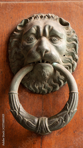 Fotografie Antique metal door knocker in the shape of a lion’s head, for knocking on a wood