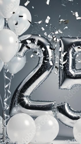 Silver foil balloons shaped as the number 25 surrounded by white balloons and confetti, creating a festive atmosphere for a celebration or anniversary event