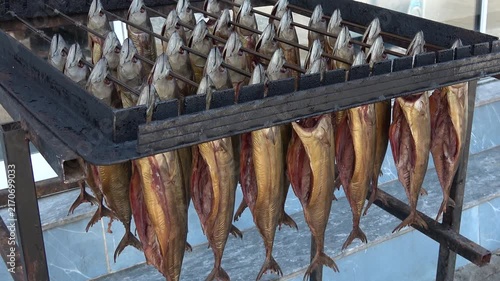 Fethiye, Turkey - 23 of August 2026: Smoked mackerel fish hanging on metal drying rack
