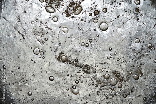 Картината върху платно A metallic surface with a reflective, textured appearance features numerous bubble-like formations encapsulated within it