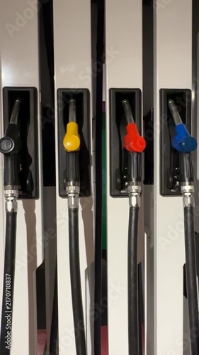 Colorful fuel pump handles aligned on a gas station dispenser arranged vertically