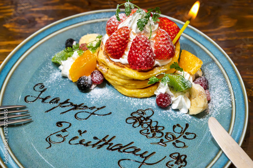 いちごとフルーツを飾った誕生日祝いのパンケーキ