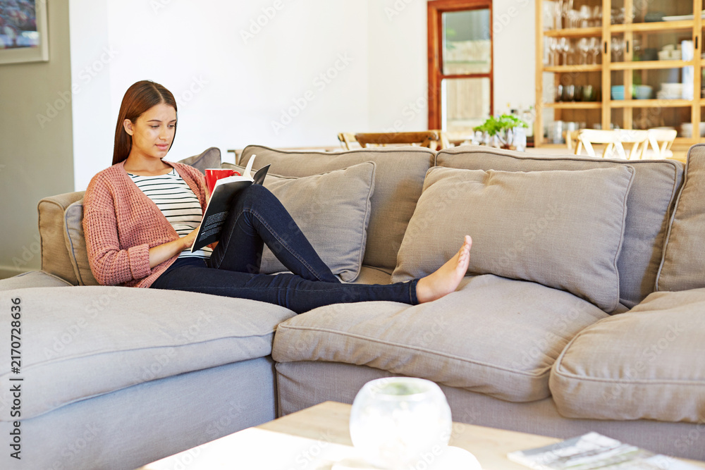 Fototapeta premium Woman, student and relax at house with reading book, fiction story and learning for language. Female person, rest and education in lounge with novel, fantasy storytelling and poetry for stress relief