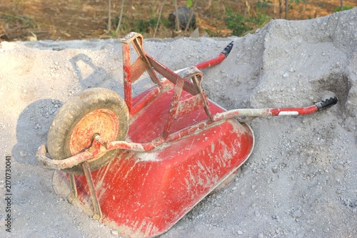 red wheelbarrow upside down on a pile of sand at a construction site