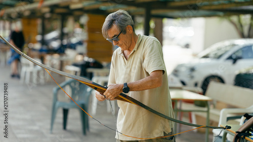 фотографія Senior man stringing a longbow, preparing for target practice outdoors
