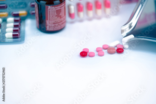 Foto Red, pink, and white tablets pills with drug tray on blurred glass drug bottle and blister pack