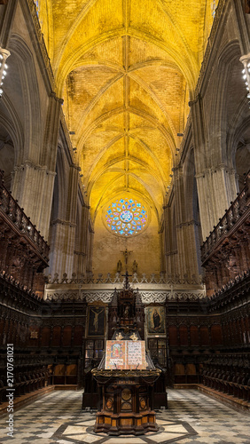 Canvastavla Grand Gothic cathedral interior viewed symmetrically along the nave, with a glowing vaulted ceiling, stained glass and richly carved choir stalls
