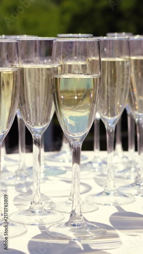 Glasses of sparkling wine shimmer in the sun outside during a festive event. Champagne is an alcoholic beverage at a banquet in an upscale restaurant.