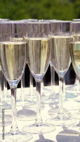 Glasses of sparkling wine shimmer in the sun outside during a festive event. Champagne is an alcoholic beverage at a banquet in an upscale restaurant.